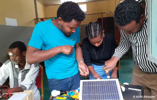 Drei Jugendliche bauen eine Solaranlage während eines Trainings im Bereich PV-Solarenergie