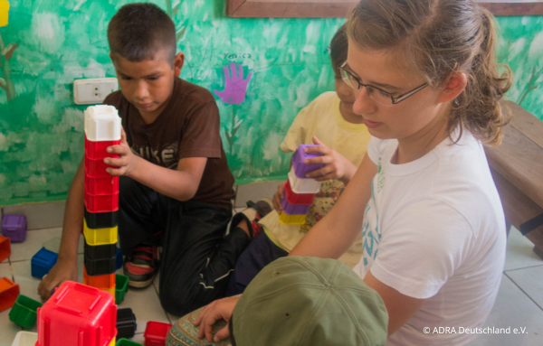 Bild von Mirjam, die während ihres Freiwilligenjahrs in Bolivien mit AdraLive einen beeindruckenden LEGO-Turm mit den Kindern baut.