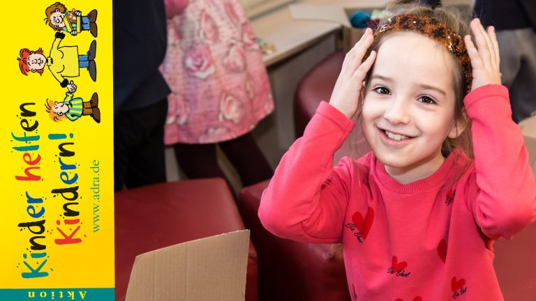Aktion Kinder helfen Kindern 2020 - Mädchen schaut lächelnd mit Blumenkrone in die Kamera