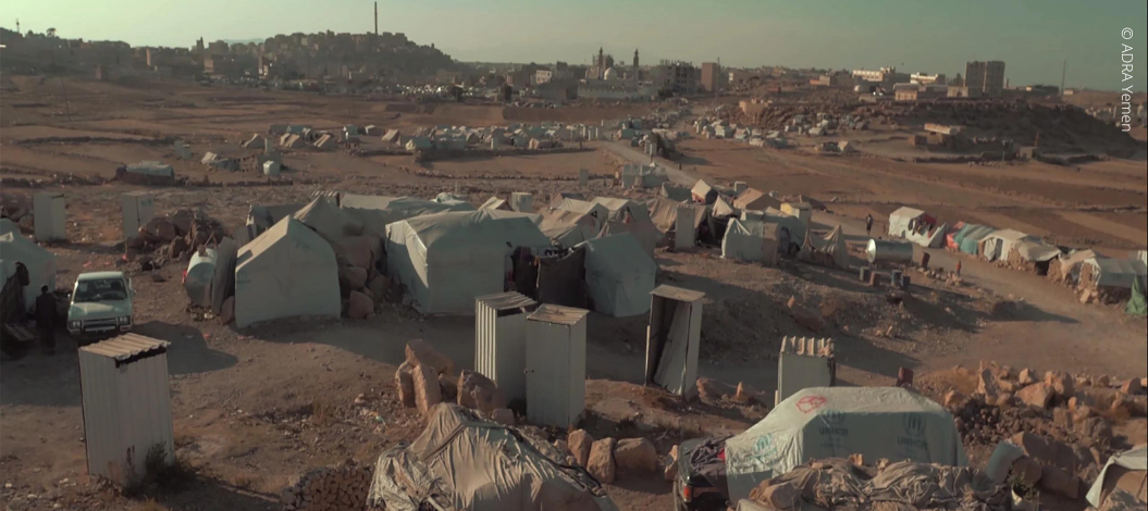 Eine Landschaft aus Zelten im Jemen. Im Hintergrund sieht man Gebäude und eine Moschee.