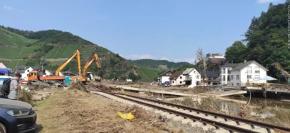 Katastrophenhilfe Hochwasser Deutschland - Bagger räumen Trümmer an einer zerstörten Brücke neben Bahngleisen in einem von Hochwasser betroffenen Tal