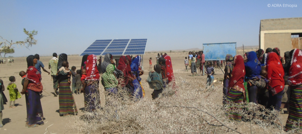 Eine Gruppe von Einwohnern in Äthiopien steht im Freien und bewundert die fertiggebaute Solaranlage.