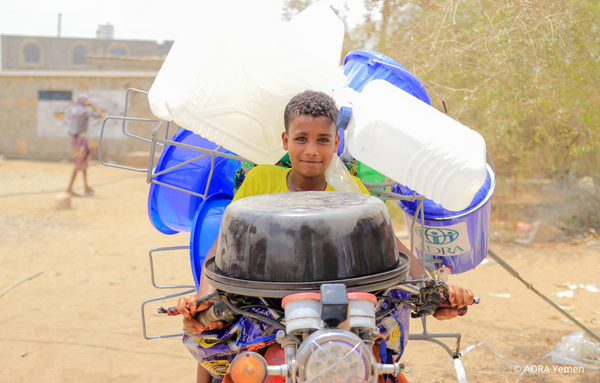Ein Junge auf einem mit Kanistern vollgepacktem Motorrad im Jemen