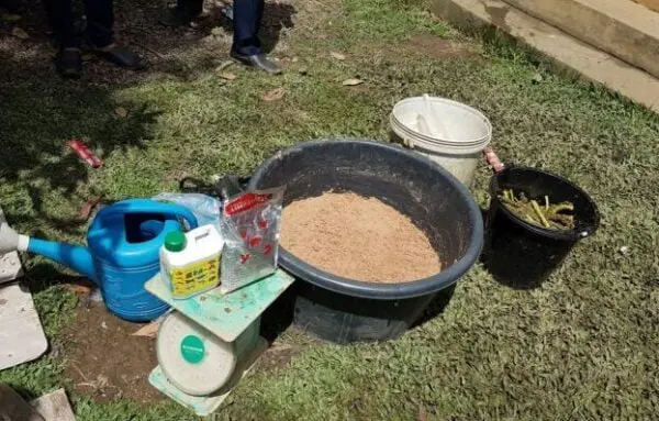 Fischfutter in Schüsseln, eine kleine blaue Gießkanne und weiteres Equipment für ein Fischzucht Training in Laos
