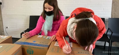 Zwei Mädchen packen und beschriften Pakete für die Aktion Kinder-helfen-Kindern