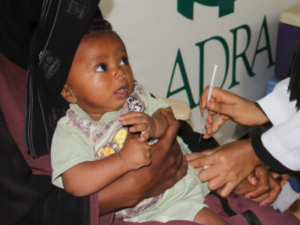 Ein Kleinkind bekommt eine Impfung von einer Ärztin auf dem Oberschenkel, während es auf dem Schoß der Mutter sitzt