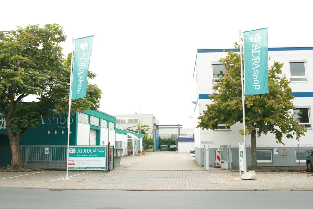 Die Einfahrt des ADRAShops in Weiterstadt, mit zwei großen grünen Fahnen