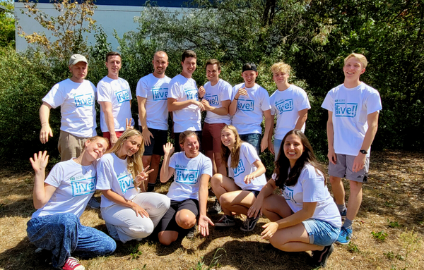 Eine Gruppe junger, glücklicher Menschen in ADRAlive-T-shirts, die sich im Freiwilligendienst im In- und Ausland engagieren.