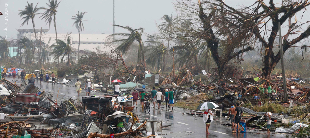 Anwohner gehen am 10. November 2013 durch die von Taifun Haiyan verwüstete, mit Trümmern übersäte Straße in Tacloban