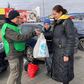 Ein ADRA-Mitarbeiter übergibt einer geflüchteten Frau aus der Ukraine eine Tüte.