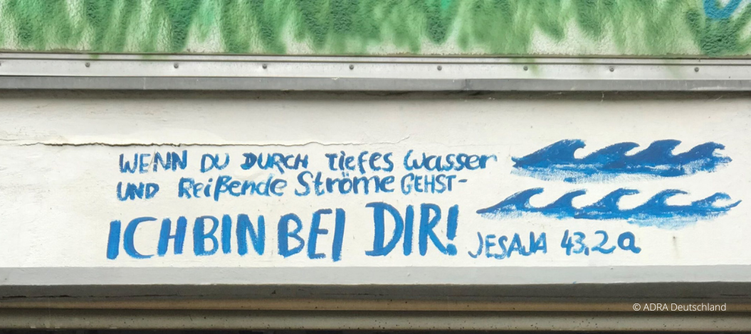 Blaue Wandaufschrift aus dem Hochwassergebiet: „Wenn du durch tiefes Wasser gehst – bin ich bei dir!“
