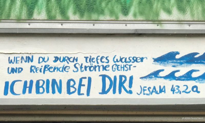 Geschrieben an einer Wand mit blauer Schrift aus dem Hochwassergebiet: "Wenn du durch tiefes Wasser und reißende Ströme gehst - bin ich bei dir!"