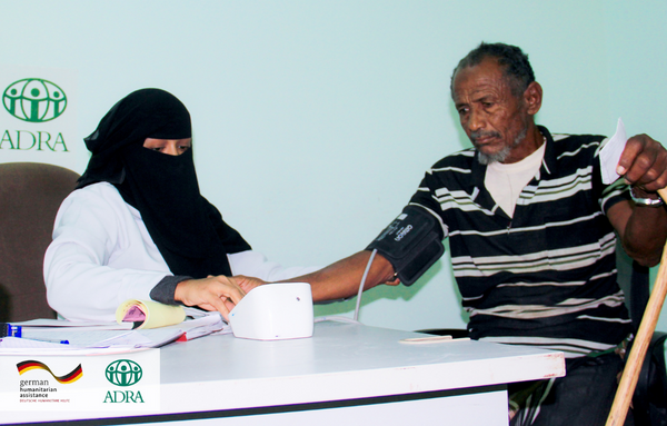 Eine Arzthelferin untersucht in einer Klinik im Jemen einen Mann mit einem Blutdruckgerät, welches an seinem Arm befestigt ist.