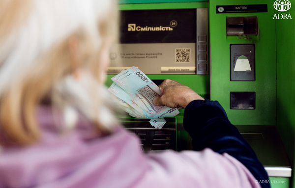 Eine Frau aus der Ukraine hebt an einem Bankautomaten Geld ab.