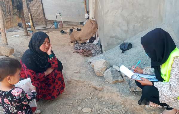 Eine ADRA-Mitarbeiterin hilft einer Frau mit ihrem Kind die Formulare auszufüllen, um Lebensmittelpakete als Nothilfe nach dem Erdbeben in Afghanistan zu erhalten.