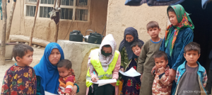 Eine ADRA-Mitarbeiterin hilft einer Gruppe von Frauen mit Kindern in Afghanistan die Formulare für Lebensmittelpakete auszufüllen