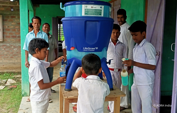Kinder aus Indien füllen Wasser in Flaschen aus einem Wassertank