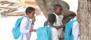 Vier junge Schüler in Somalia mit ihren hellblauen Rucksäcken, sind auf dem Weg zur Schule.