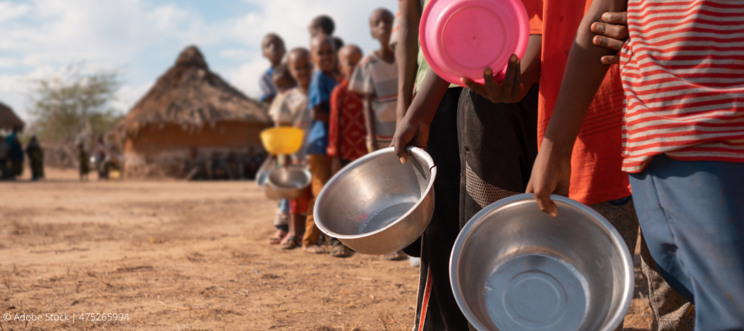 Kinder stehen hintereinander in einer Reihe und halten leere Schalen in den Händen