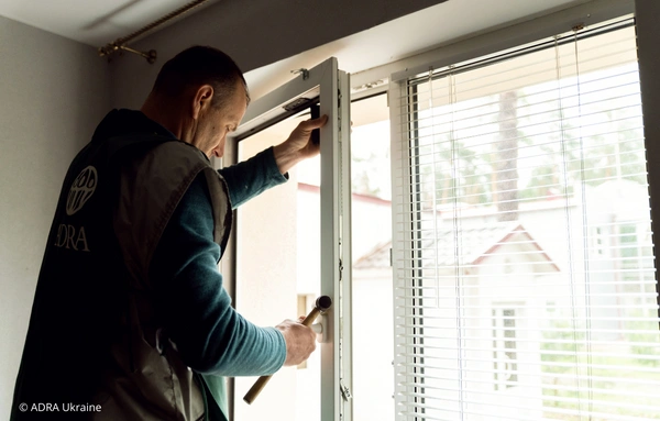 Ein ADRA- Mitarbeiter isoliert beschädigte Fenster in der Ukraine