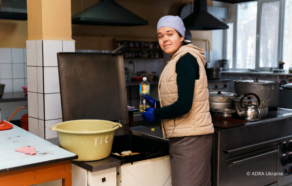 Eine Frau in einer Küche in der Ukraine, die Nahrung zubereitet, um bedürftigen Menschen während der Winterhilfe zu helfen.