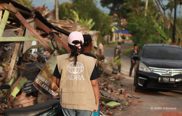 Eine ADRA-Mitarbeiterin läuft auf einer Straße in Cianjur, die von Trümmern nach einem Erdbeben übersät ist.