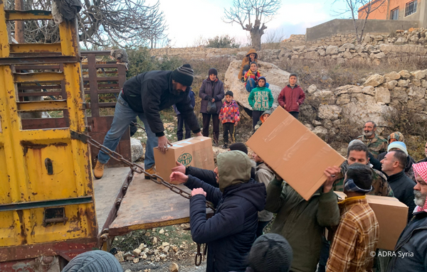 ADRA Mitarbeiter und freiwillige Helfer verteilen aus einem Laster Lebensmittelpakete im Erdbebengebiet in Syrien für die Erdbebenbetroffene