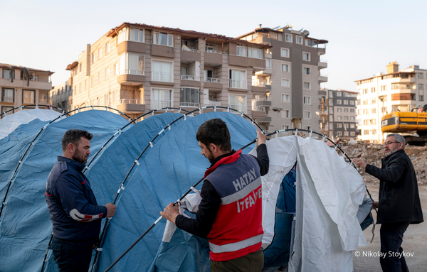 Drei freiwillige Helfer bauen Zelte, für die vom Erdbeben betroffenen Menschen in der Türkei auf.