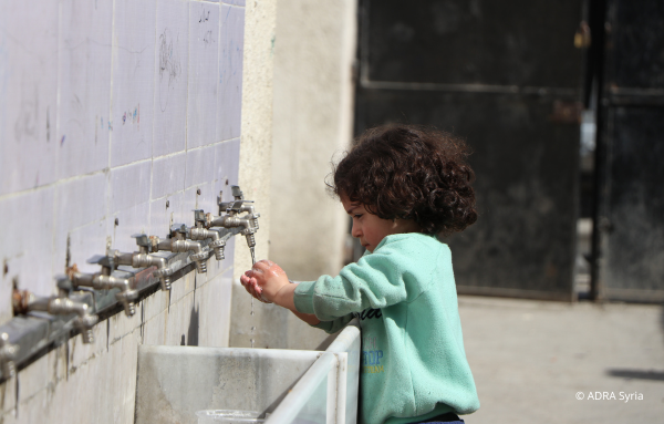 Ein Kind aus Syrien wäscht sich die Hände an den von ADRA reparierten Wassersystemen