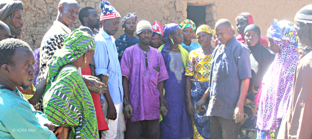 eine Menschengruppe aus Mali steht im Freien, gekleidet in farbenfrohen traditionellen Gewändern