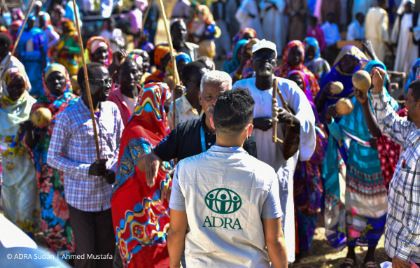 Ein ADRA-Mitarbeiter steht inmitten einer engagierten Menschengruppe im Sudan, die gemeinsam für positive Veränderungen eintritt.