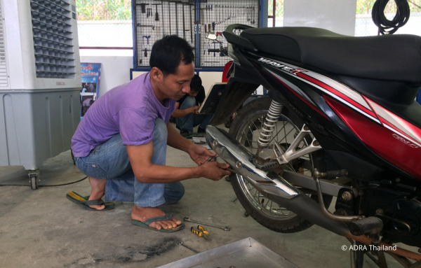 Ein Mann aus Thailand repariert sein Mofa mit Geschick und Hingabe