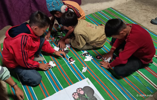 Geflüchtete Kinder in Indien spielen gemeinsam ein Puzzle, während sie Freude und Unterhaltung in ihrer neuen Umgebung finden.