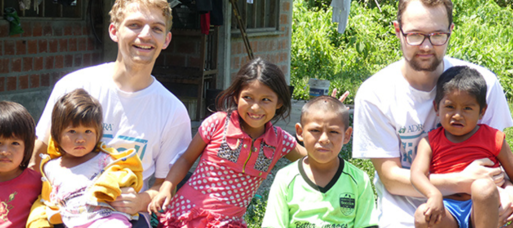Tobias und ein weiterer Freiwilliger sitzen mit fünf Kindern in einem Dschungel in Bolivien.