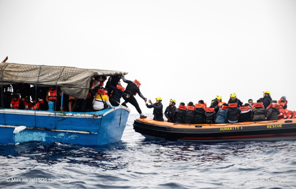 Ein Rettungsboot von SOS Humanity bringt Menschen sicher von einem anderen Boot in Sicherheit.