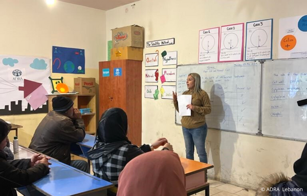 Informative Schulung im Libanon: Eine engagierte Frau steht vorne und hält eine aufklärende Rede vor aufmerksamen Teilnehmenden.