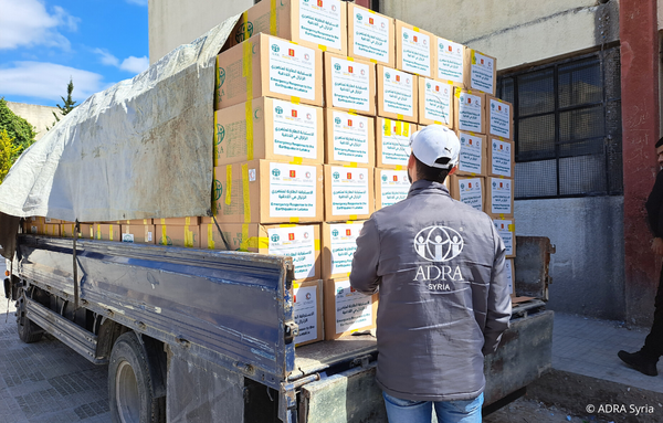 Ein ADRA-Mitarbeiter aus Syrien steht vor einem vollgeladener ADRA-LKW mit Hilfspaketen für die Erdbebenbetroffenen in Syrien