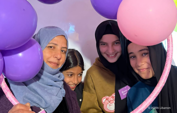 Vier junge Frauen schauen durch einen Ring mit Luftballons in die Kamera