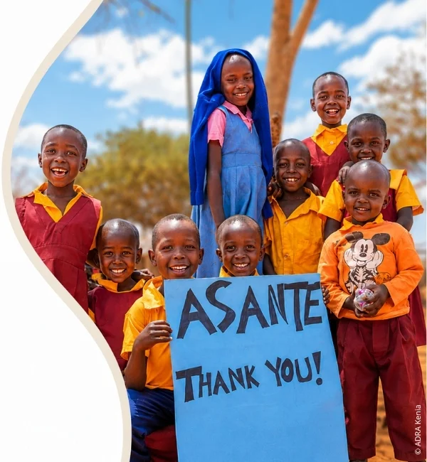 Kinder in Schuluniformen in Kenia winken fröhlich und halten ein Schild mit der Aufschrift „Asante – Thank You!