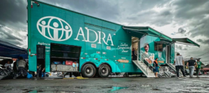 Ein grüner Truck mit der Aufschrift ADRA steht vor einer gewaltigen Wasserlache