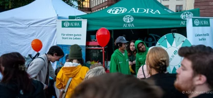 ADRA-Stand auf dem Schlossgrabenfest 2024 mit einer Drehscheibe für Gewinne, einer Popcornmaschine und grüne ADRA-Luftballons, die Besucher anziehen