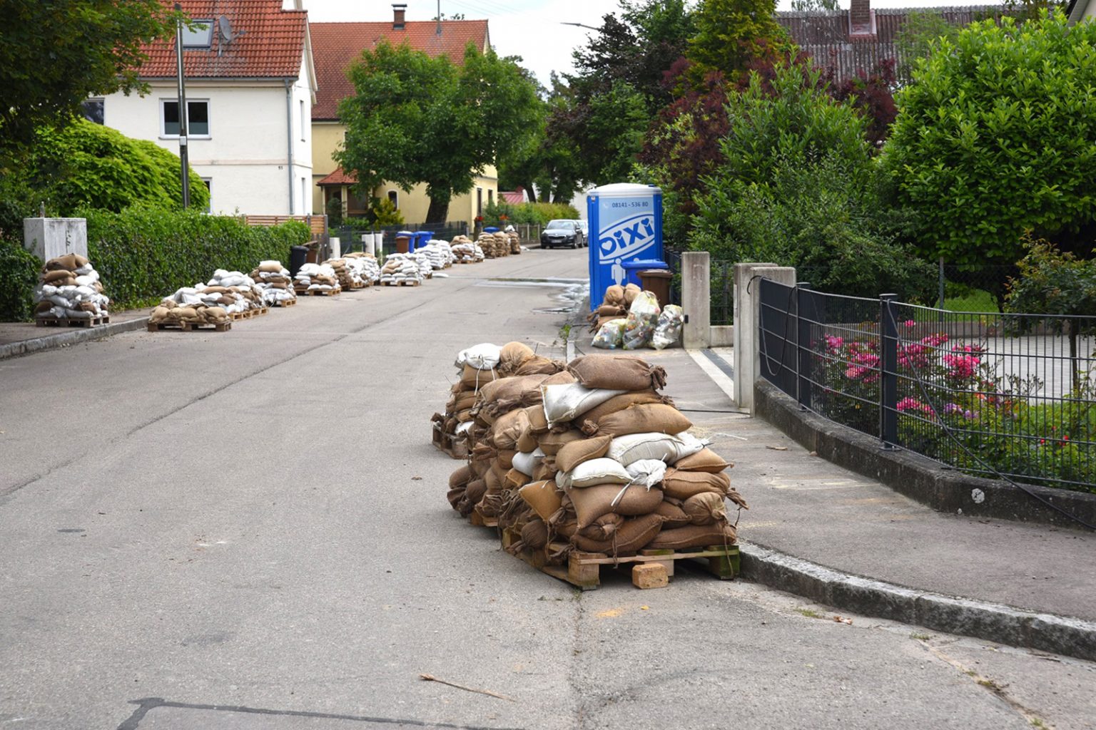 Ein Stapel von Sandsäcken auf Paletten in einer Straße in Hamlar, Landkreis Donau-Ries. Die Szene zeigt die Spuren des Hochwassereinsatzes, bei dem die Sandsäcke genutzt wurden, um die Fluten einzudämmen.