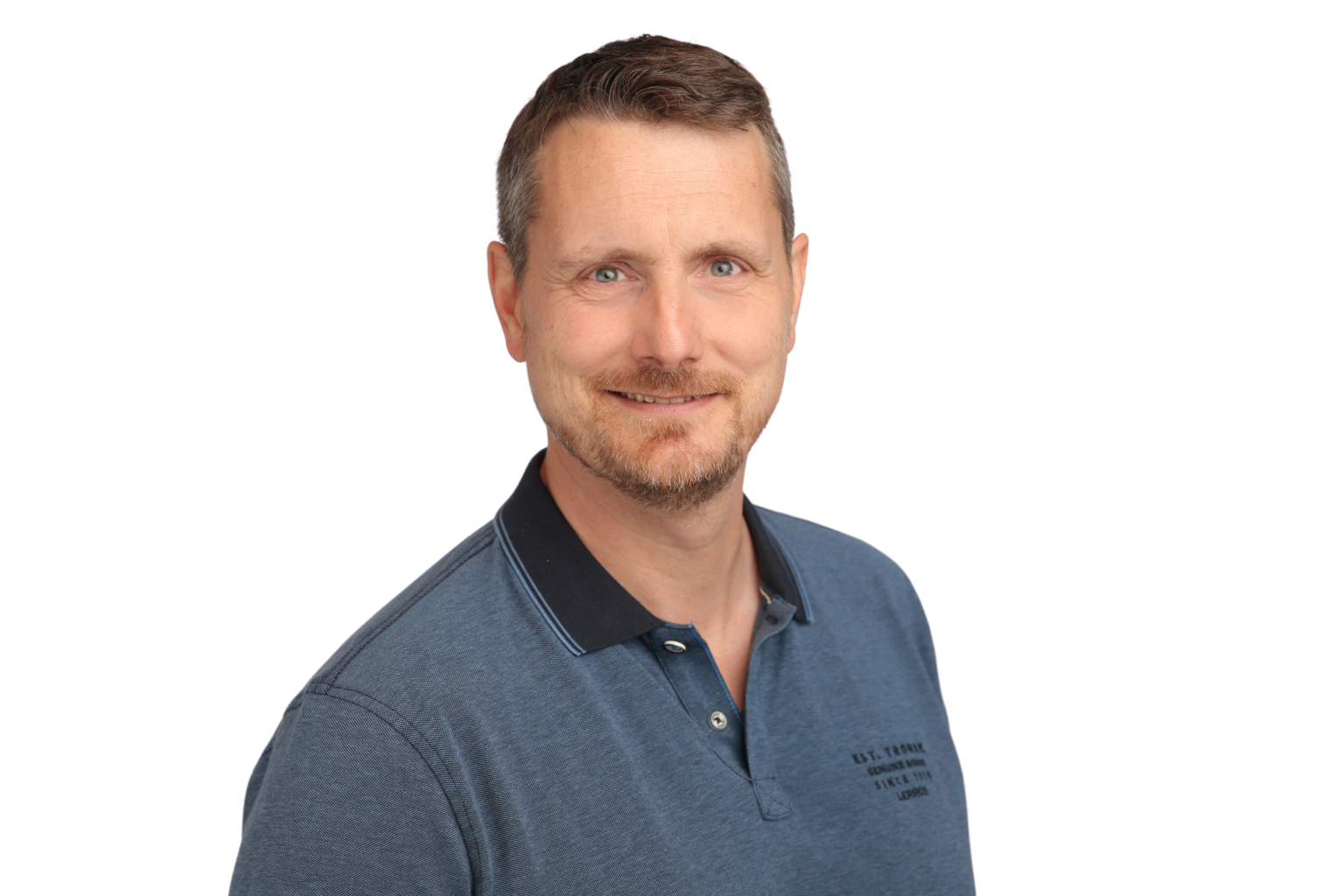 Porträt eines ADRA-Mitarbeiters mit blauem Poloshirt vor weißem Hintergrund.