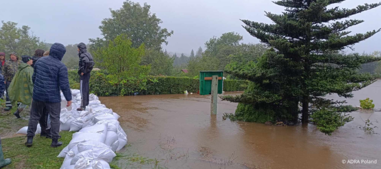 Überflutete Straße mit ADRA-Helfern im Einsatz.
