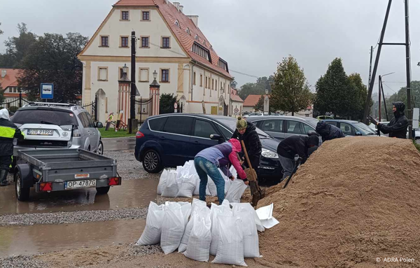 Freiwillige und Einsatzkräfte füllen Sandsäcke auf den Straßen einer vom Hochwasser bedrohten Gemeinde in Mittel- und Osteuropa. Die Sandsäcke werden verwendet, um Überschwemmungen einzudämmen und Häuser sowie Infrastruktur zu schützen.