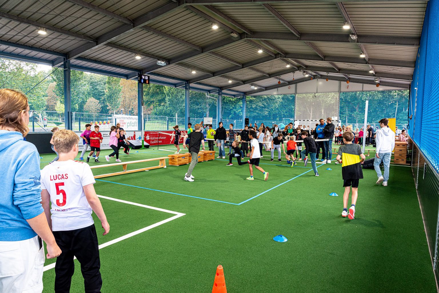 Die Kaltluft-Sporthalle ist eine stabile Stahlkonstruktion mit einem Dach. Die Wände bestehen aus einer Bande und Ballnetzen. Die LED-Beleuchtung macht die Halle in der dunklen Jahreszeit nutzbar. Sie eignet sich für Ballsportarten aber auch Gymnastik, denn die Halle hat keinen Hartboden, sondern einen „weichen“ Kunstrasenbelag.