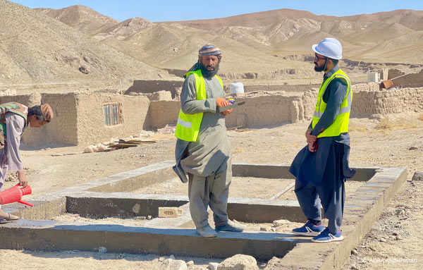 Nach dem Erdbeben in Herat: Betroffener Mann zeigt auf Trümmer, ADRA-Mitarbeiter leistet mitfühlend Hilfe.