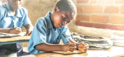 Kind schreibt im Klassenraum – Spenden für Bildung ermöglichen Schuljahr mit Gebühren, Uniform und Lehrmaterial.