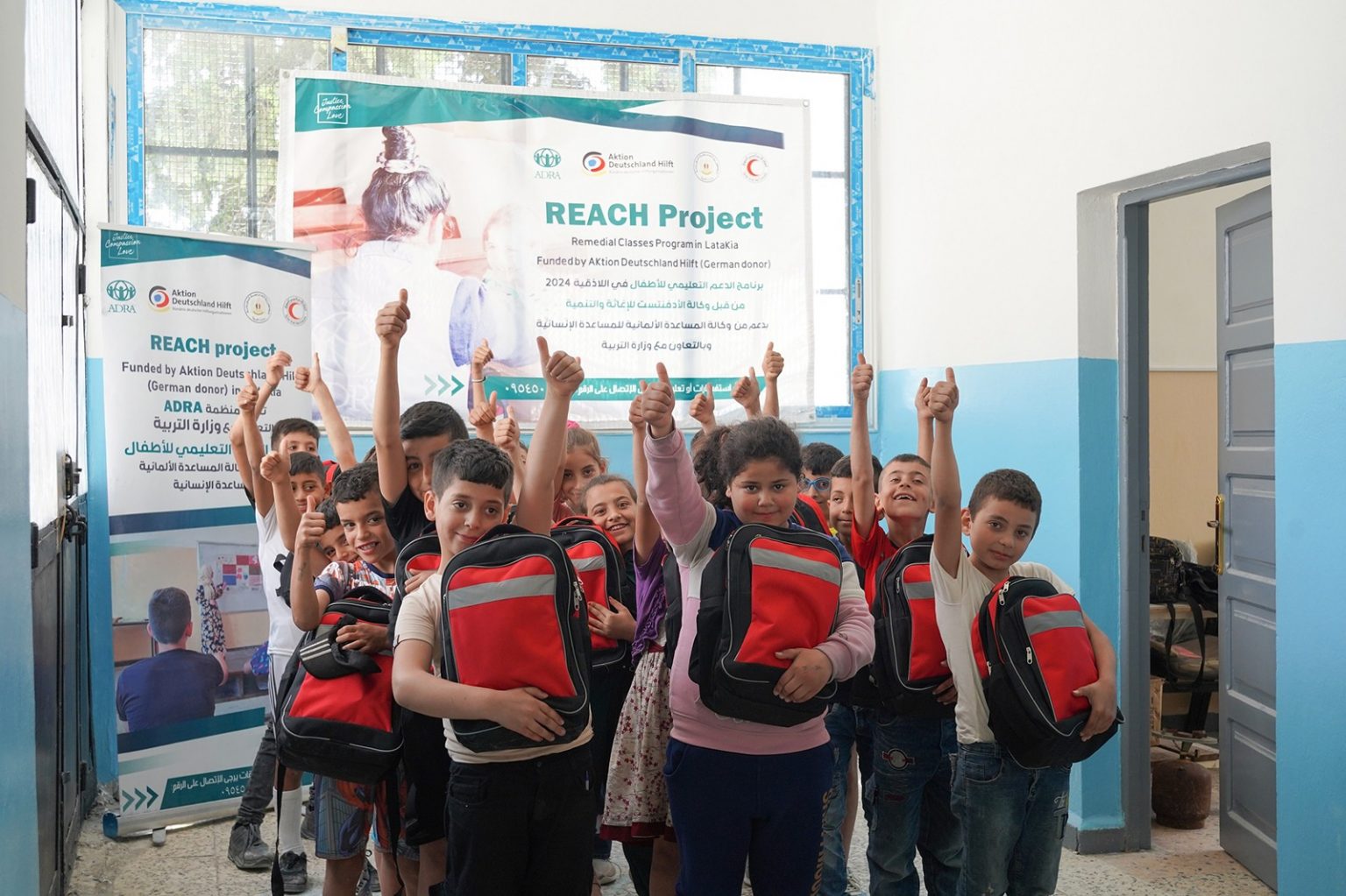 Eine Gruppe von Kindern lächelt glücklich und hält stolz ihre neuen Schulranzen in den Händen.