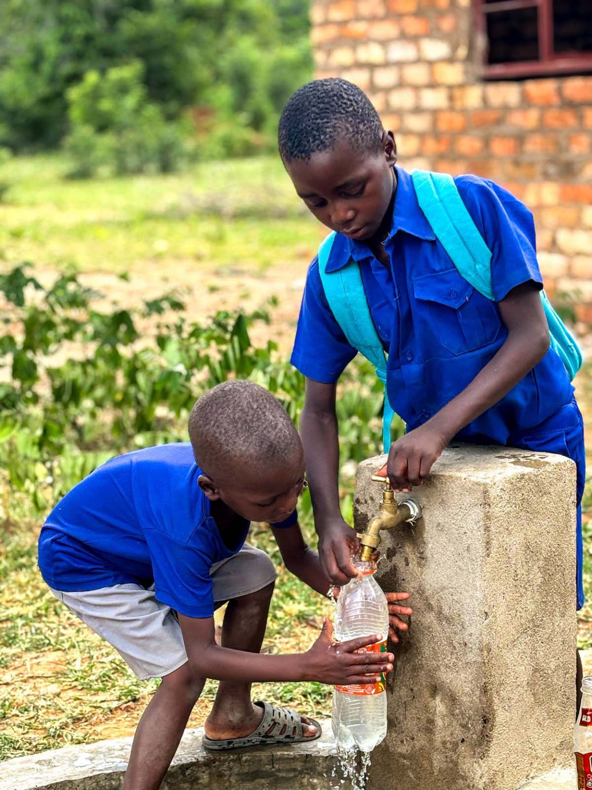 Ein Kind hält eine Flasche unter einem laufenden Wasserhahn, um sie mit Wasser zu befüllen
